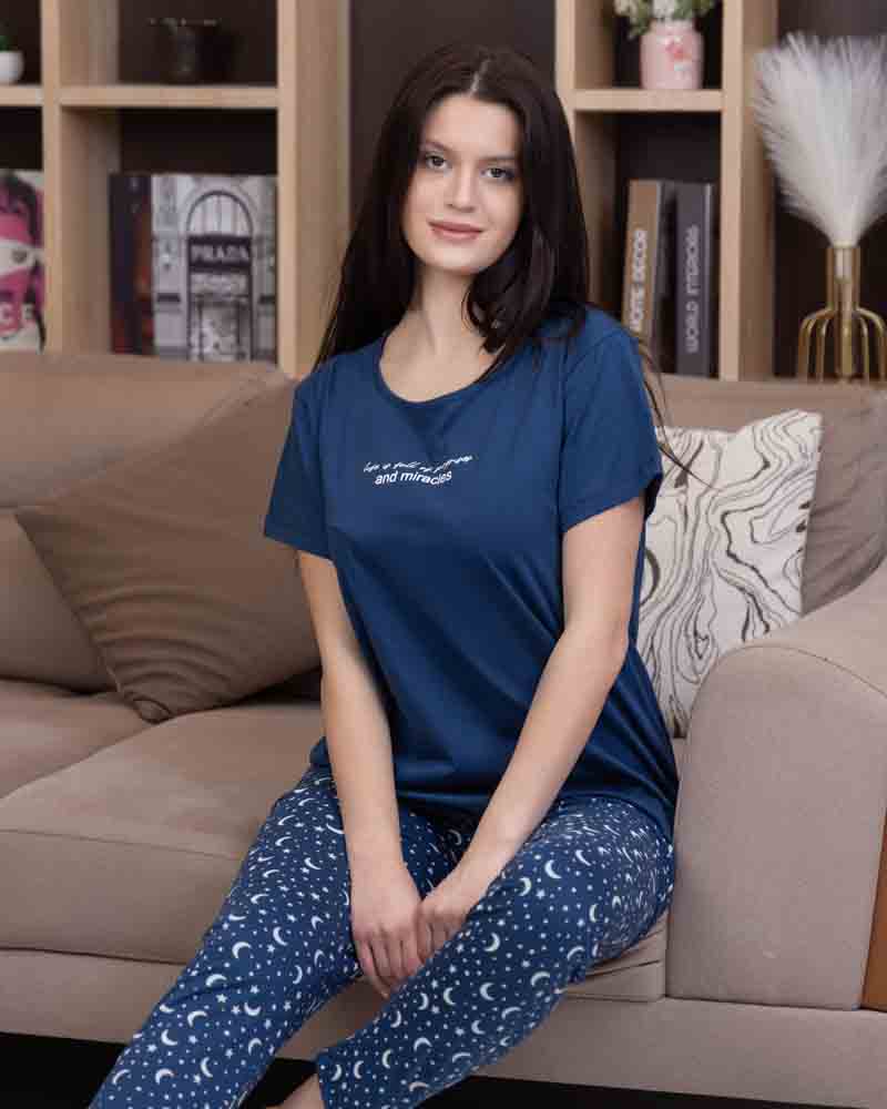 تي شيرت أزرق نص كم بطبعة كتابية صغيرة مع بنطلون طويل أزرق بنقشة هلال ونجوم باللون الأبيض في وضع الجلوس