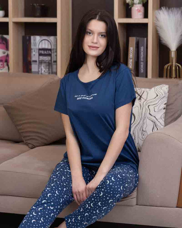 تي شيرت أزرق نص كم بطبعة كتابية صغيرة مع بنطلون طويل أزرق بنقشة هلال ونجوم باللون الأبيض في وضع الجلوس